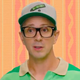 Blue's Clues host Steve Burns in a baseball cap and green shirt in front of an orange and pink background.
